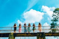 夏日明媚的天空下，一群年轻女子站在桥上，享受着休闲时光