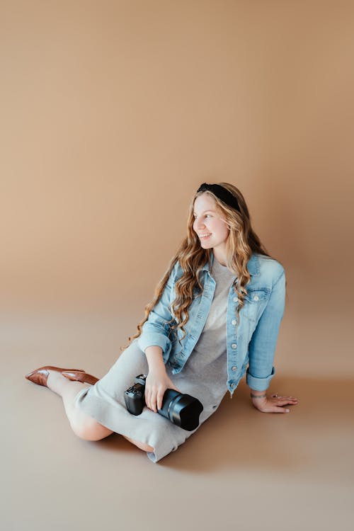 Free Young Woman Sitting on Floor with Photo Camera with Telephoto Lens Stock Photo