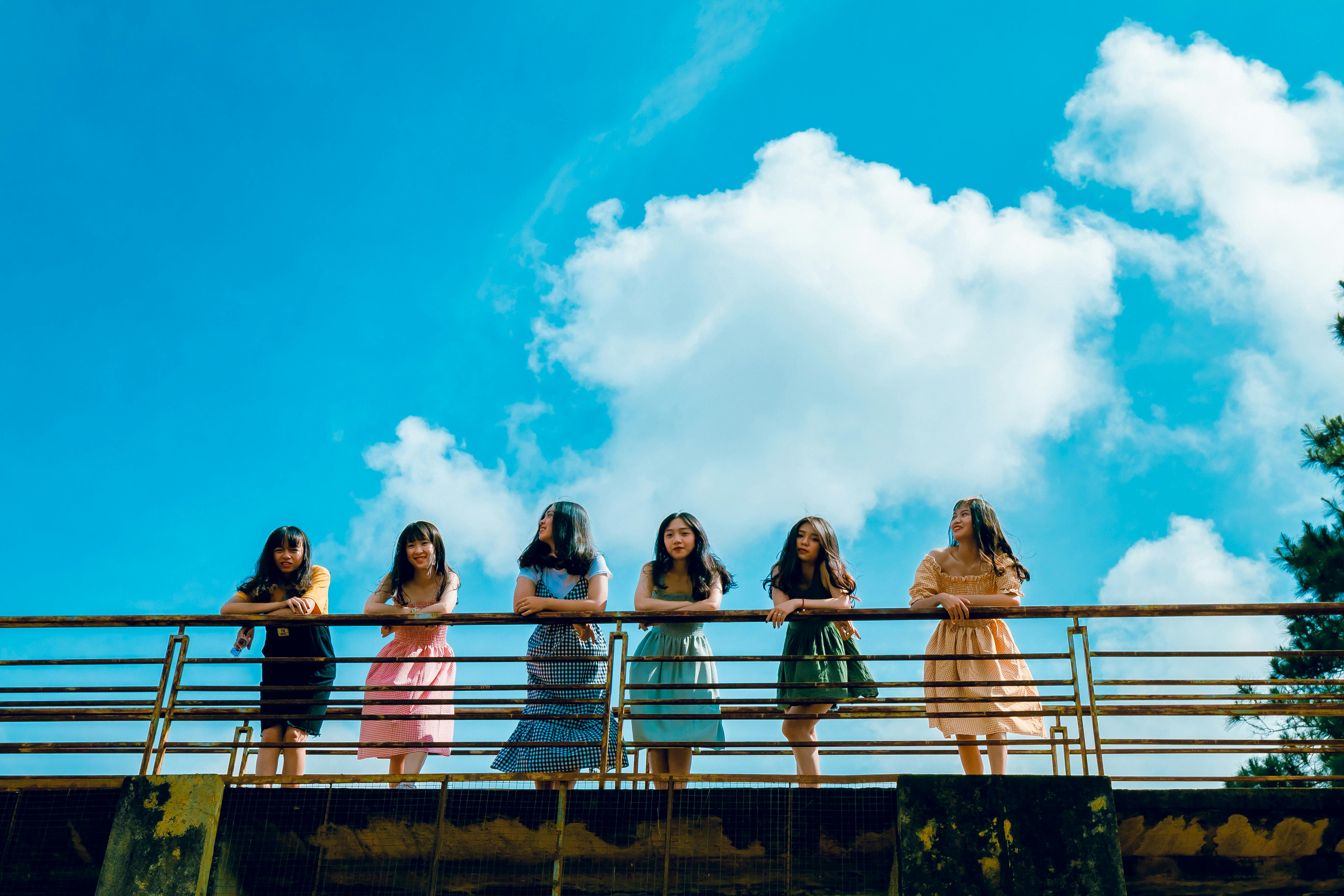 六名妇女站在蔚蓝天空下的桥上，在户外享受着阳光明媚的一天