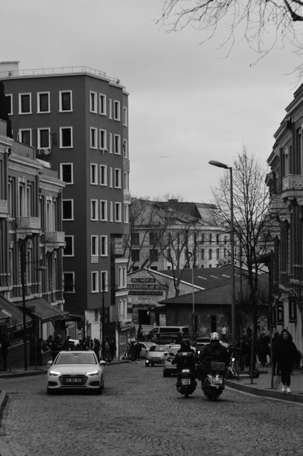 Monochrome view of a busy İstanbul street with cars and pedestrians, capturing urban life.