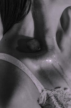 Black and white close-up of a woman's clavicle with ice melting on her skin.