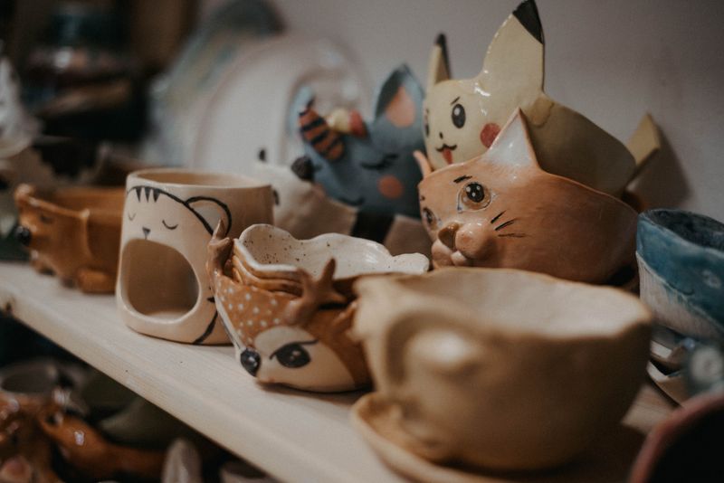 Handmade ceramic cups shaped like cats and deer on a shelf