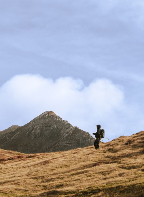 Free A solitary hiker navigates the rugged mountain slopes under a blue sky in Shkodër, Albania. Stock Photo