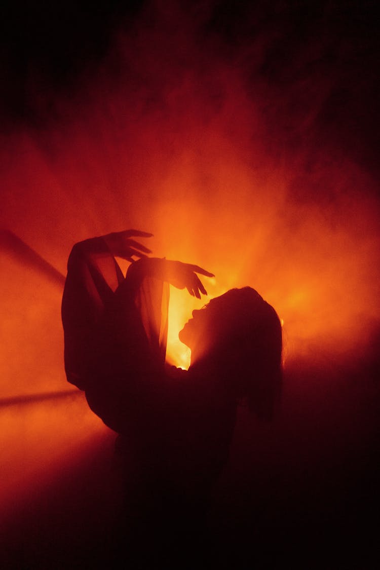 Back Lit Silhouette Of Woman With Arms Raised