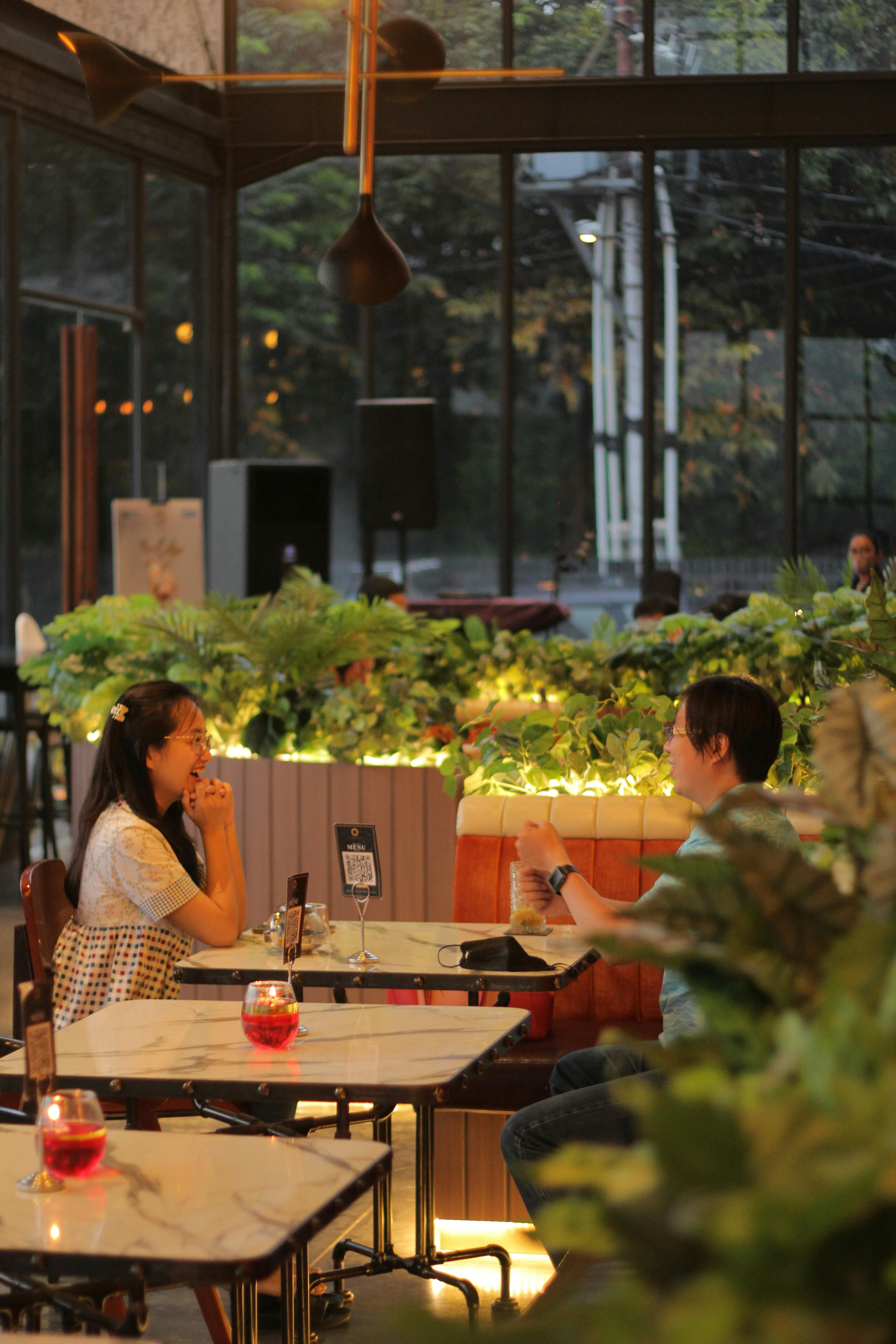 A couple enjoying dinner in a stylish indoor restaurant with lush greenery.