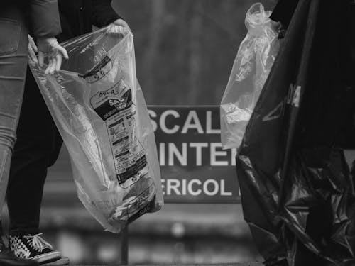 Black and White Shot of People Holding Garbage Bags