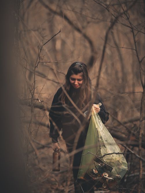 Free A woman in black long sleeves cleaning up litter in a forest with a focus on environmental care. Stock Photo