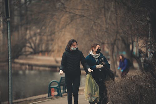 Women in Face Masks Collecting Garbage in Park