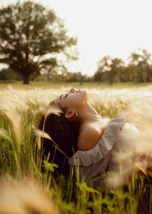 Free Woman Laying in Grain Field with Head Tilted Back Stock Photo