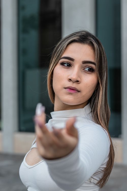 Free Close-up of a young woman reaching with focus and intent in an urban environment. Stock Photo