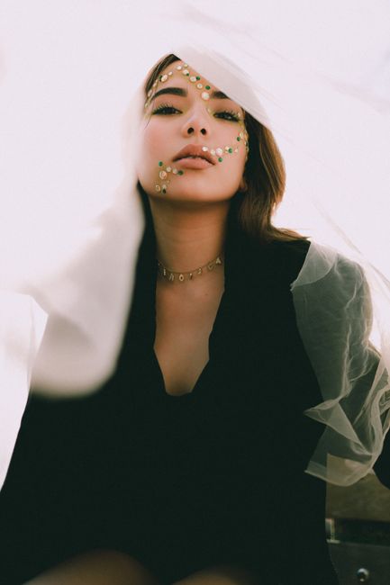 Beautiful model with glittery makeup and sheer fabric, creating a dreamy and artistic portrait.