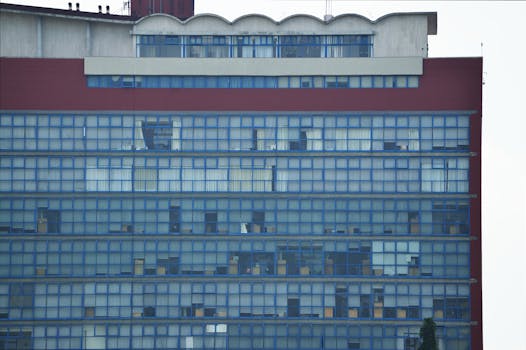 特写镜头中，一座高大的现代建筑映入眼帘，蓝色玻璃窗与红色点缀相映成趣