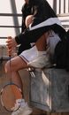 A Person in Black Jacket and White Shorts Sitting while Holding a Badminton Racket