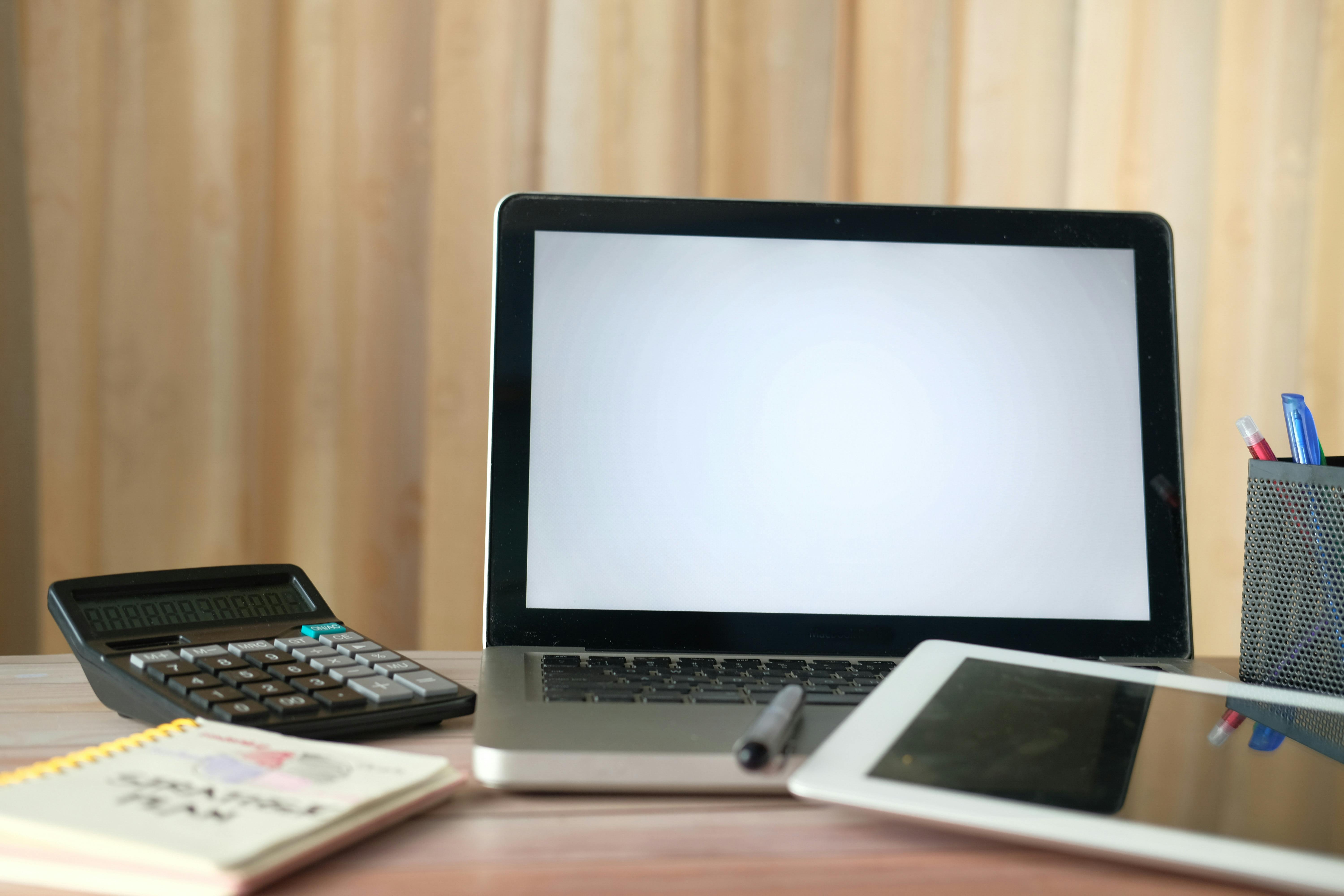 Organized office desk with a laptop, calculator, and tablet ready for business tasks.