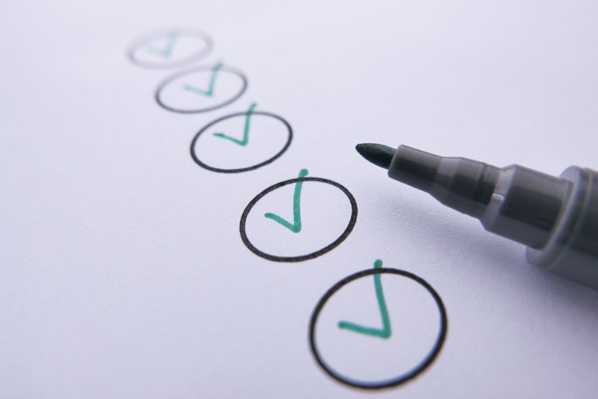 Checklist marks on white paper next to a pen.