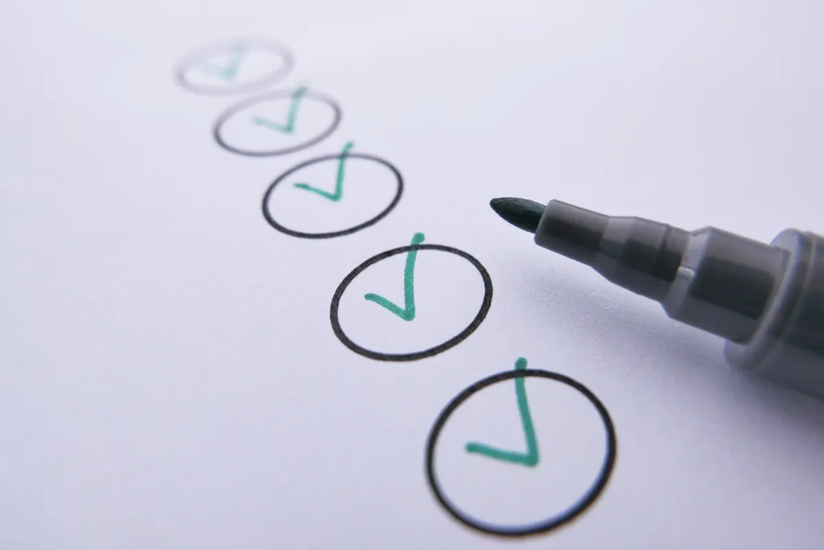 A checklist of five hand-drawn circles, each with a green tick, next to the tip of a gray marker pen.