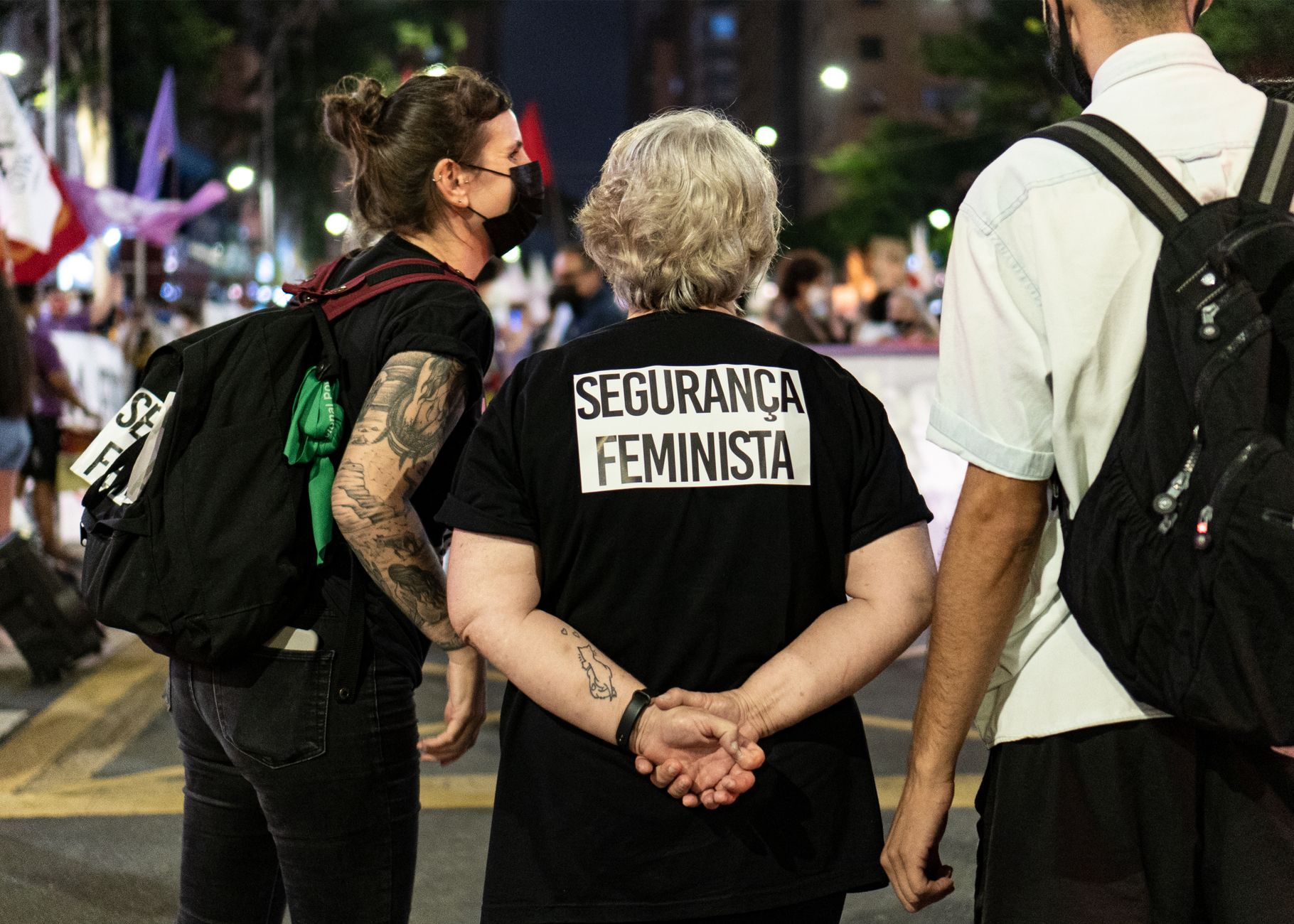 Feminist security activists in masks gather at a night protest rally outdoors.