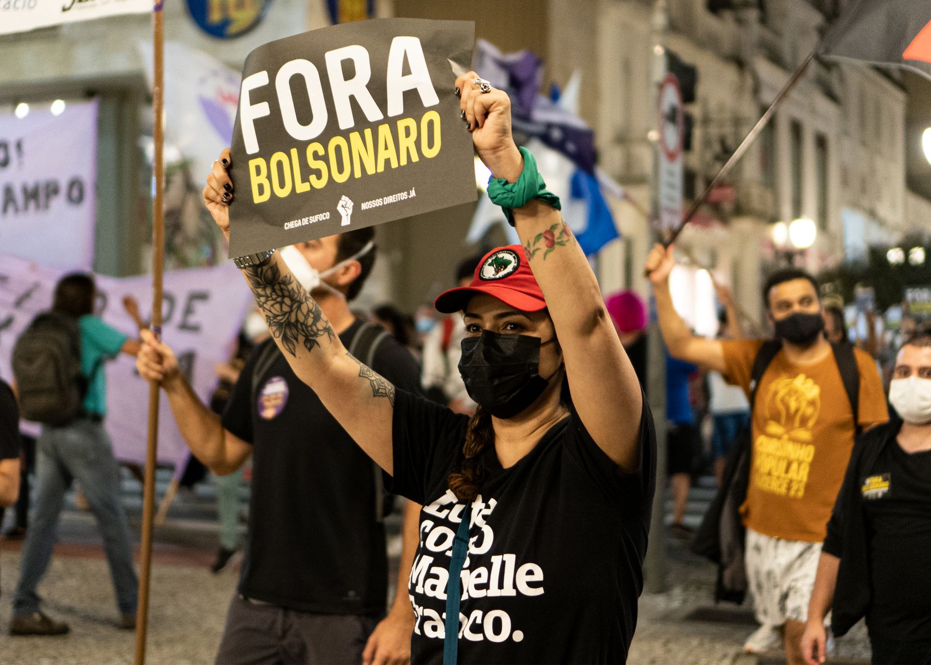Demonstrators protesting against Bolsonaro, holding signs on a city street.