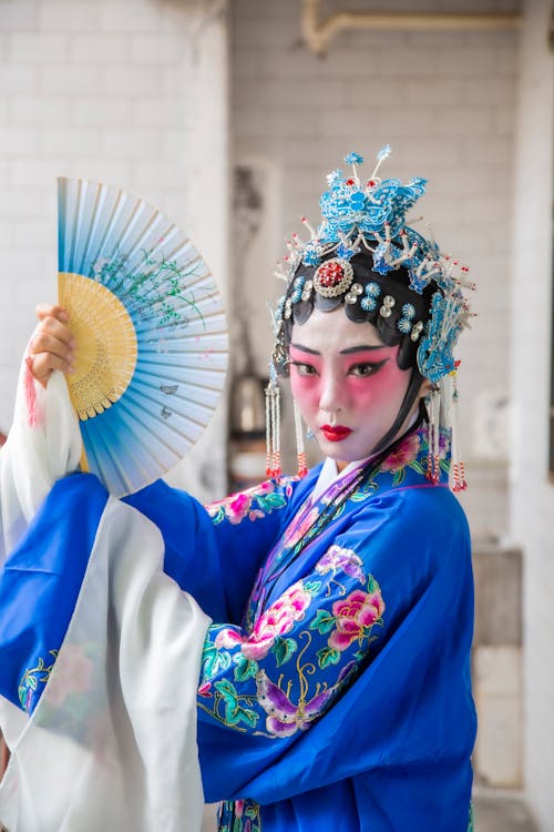 A Woman in Blue Traditional Clothes Holding Hand Fan