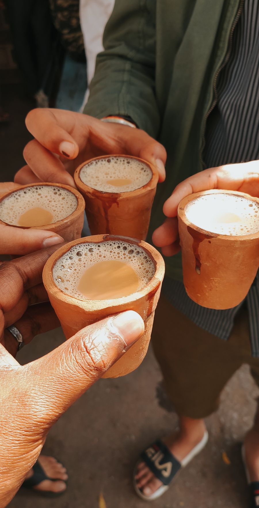 Five friends raising clay cups of masala chai