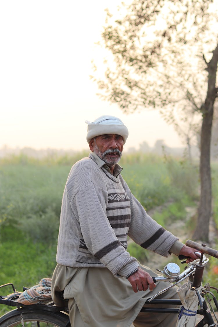 An Elderly Man Riding A Bike On The Street