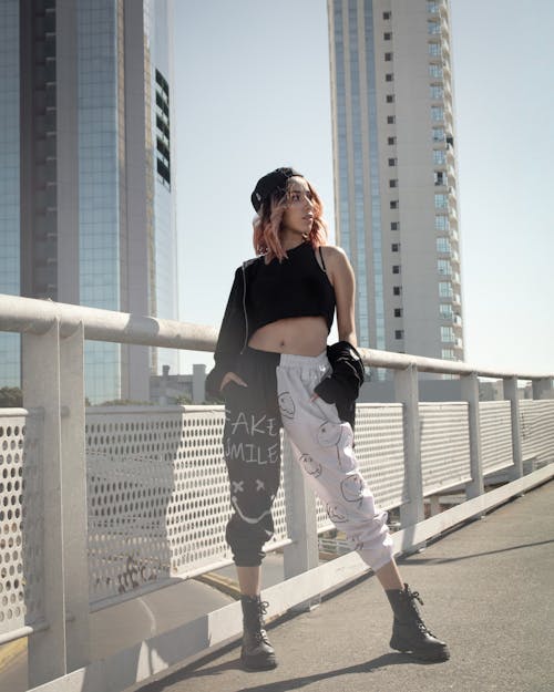 Woman in Black Tank Top and White Pants Standing on White Bridge