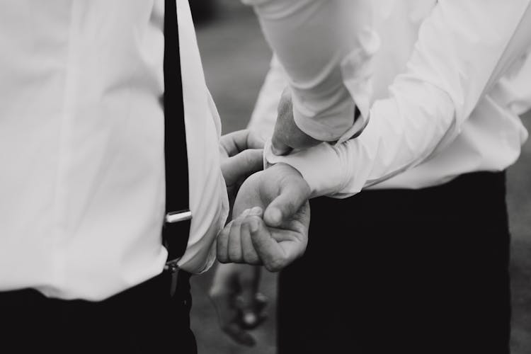 Grayscale Photo Of A Person Fixing Another Person's Cuff