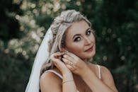 Blond Woman with White Veil in Hair Fastening Earring