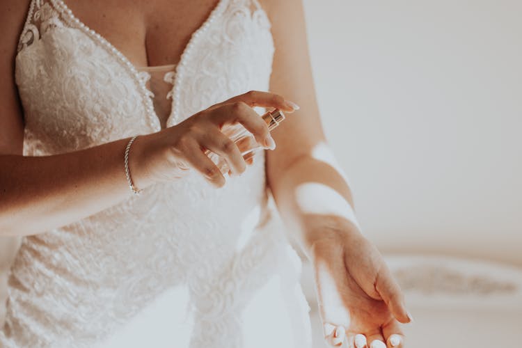 Unrecognizable Woman In White Lacy Dress Spraying Perfume On Wrist