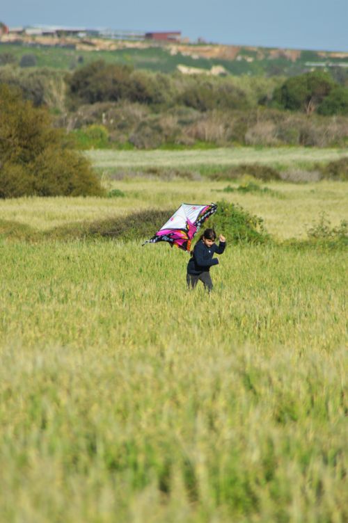 Free A child joyfully runs with a colorful kite in a sunlit rural landscape. Stock Photo