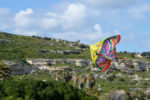 colourful kite against green hills and blue sky