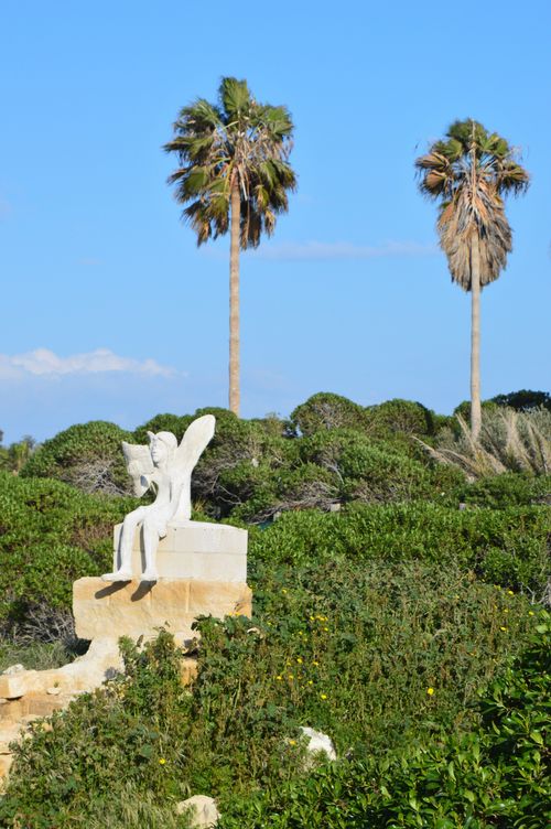 Free statue of fairy angel reading book under palm trees Stock Photo
