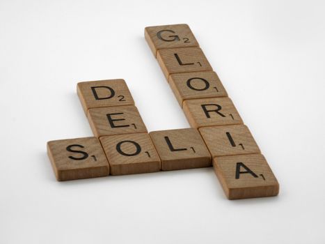 Scrabble tiles spelling 'Soli Deo Gloria' in a minimalist still life on white background.