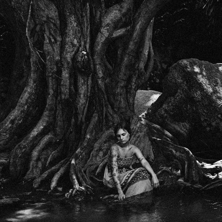 Tattooed Woman Sitting On Tree Roots