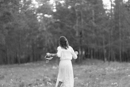 Grayscale Photo of  a Woman Running on a Grass Field