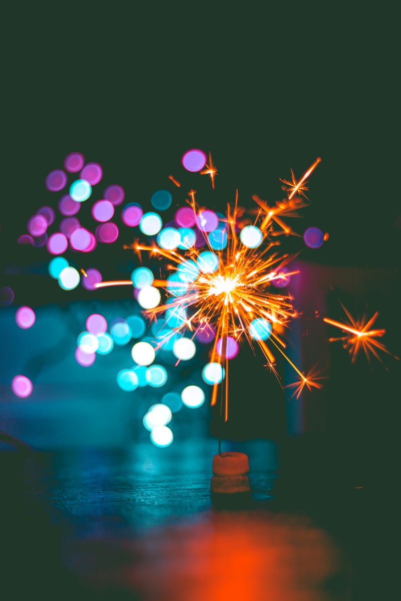 Dynamic sparkler igniting against colorful bokeh background