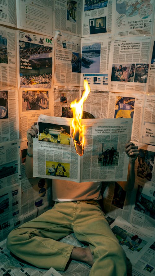 Person Holding a Burning Newspaper