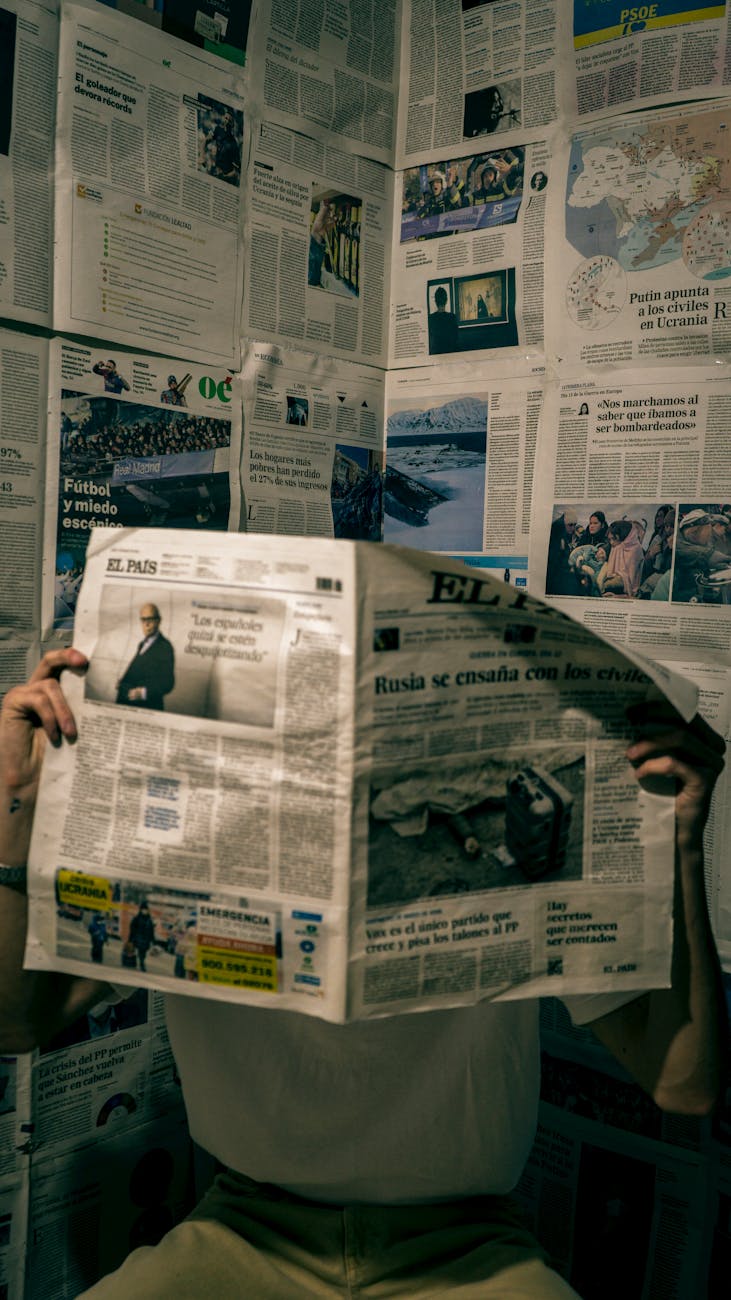 Person reading a newspaper in a room with walls full of news articles, reflecting the UAEThrive Daily News Roundup and staying informed in the UAE