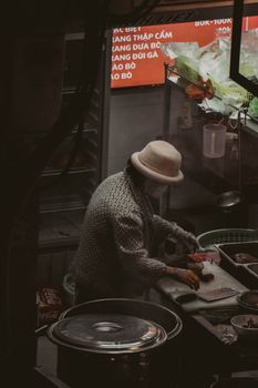 A woman prepares food at an outdoor food stall, showcasing street culinary arts.
