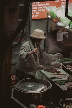 A street vendor prepares traditional Asian cuisine in a bustling market setting.
