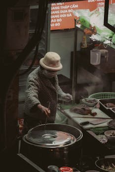 A woman street vendor preparing food in an urban outdoor setting at night.