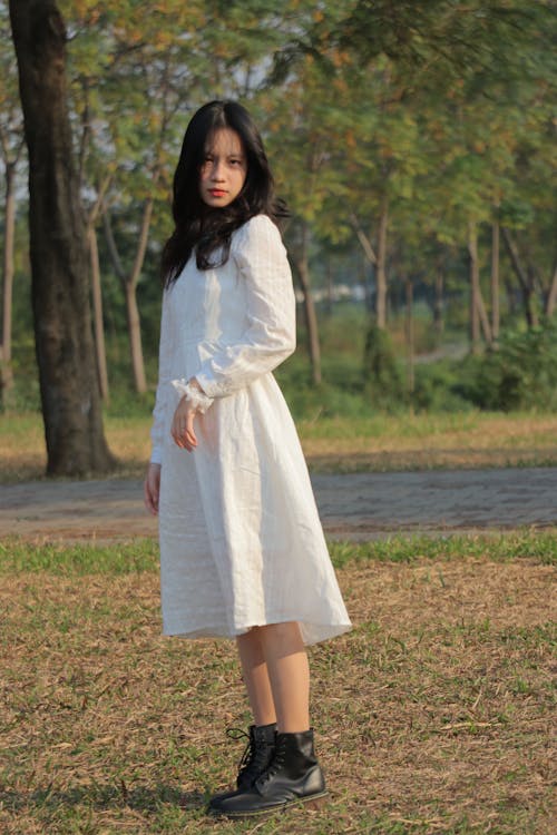 A Woman in White Long Sleeves Dress Standing on the Grass