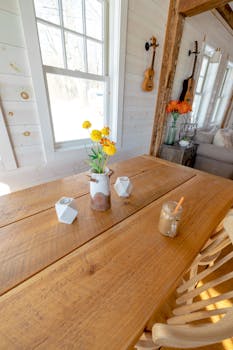 Rustic dining table with yellow flowers and musical decor in a sunlit Vermont home.