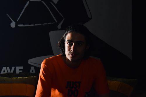 Free A man in an orange shirt sits pensively in low light, creating a dramatic effect. Stock Photo