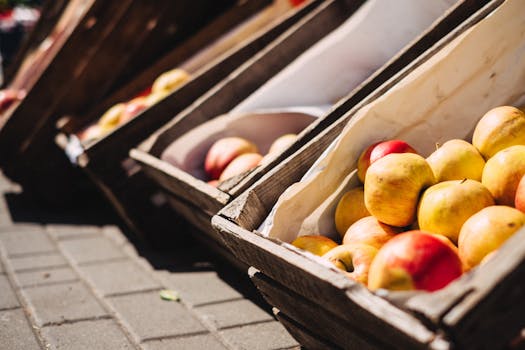 Vibrant apples displayed in rustic wooden crates at a lively outdoor market.