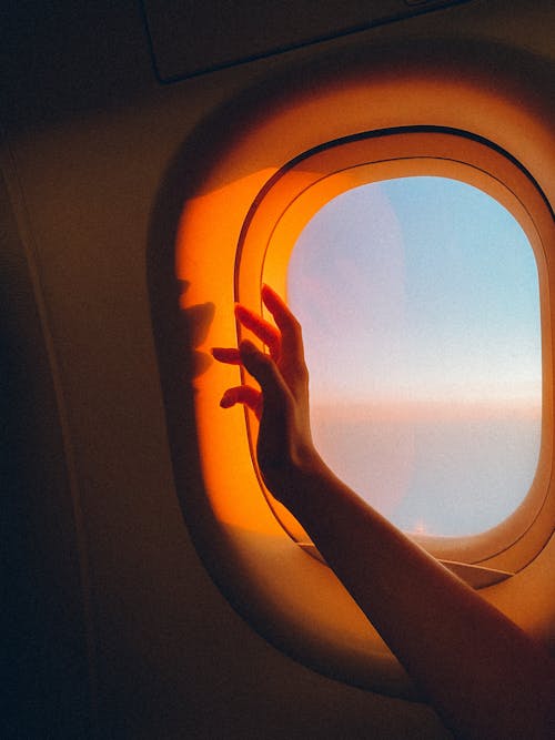 Arm Over Plane Window at Sunset