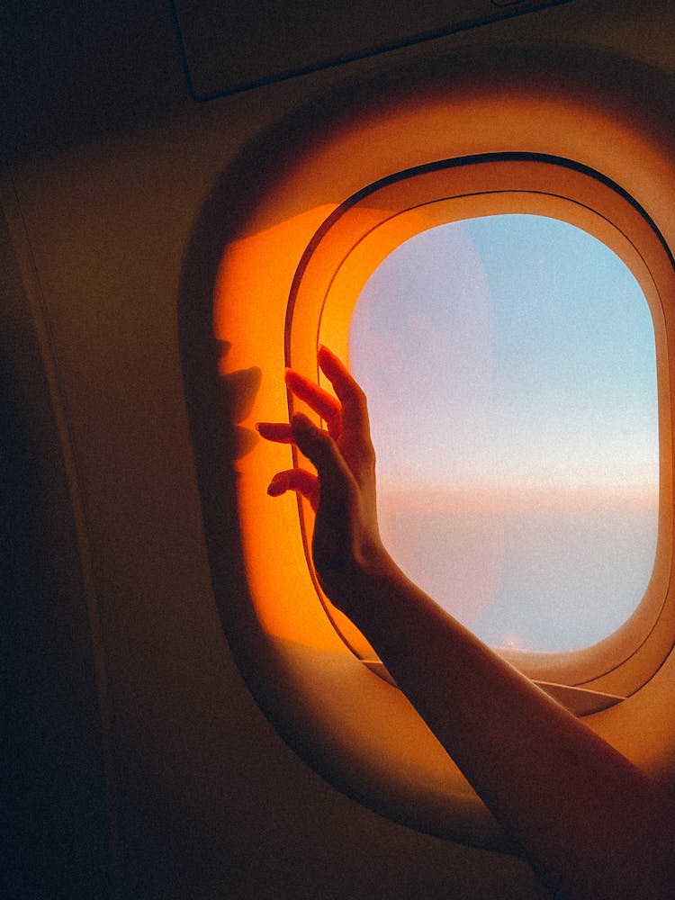 Arm Over Plane Window At Sunset