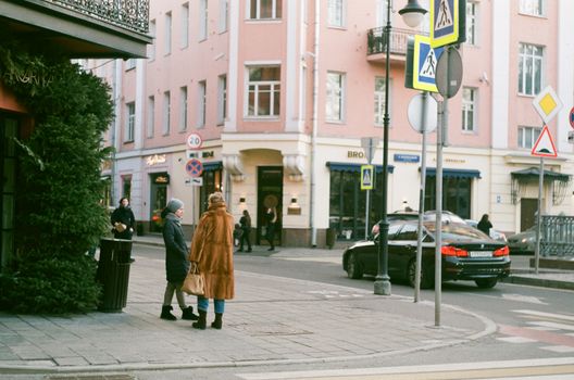 Urban street scene in Moscow with pedestrians and cars in winter.