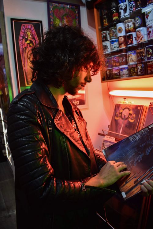 Free A man with curly hair browsing vinyl records in a neon-lit store in Seville, Spain. Stock Photo