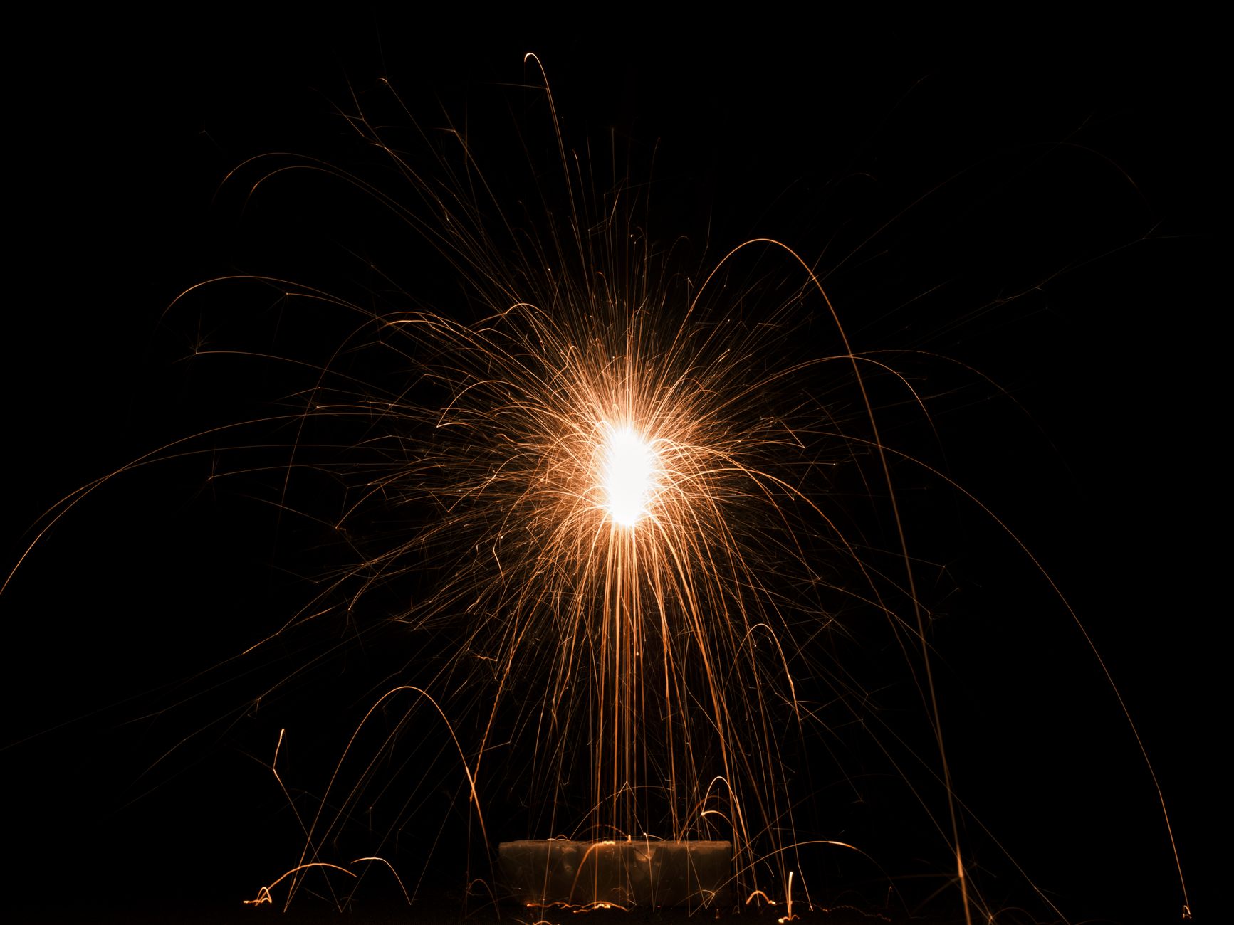 A captivating close-up of golden sparks from a fireworks display illuminating the dark night sky.